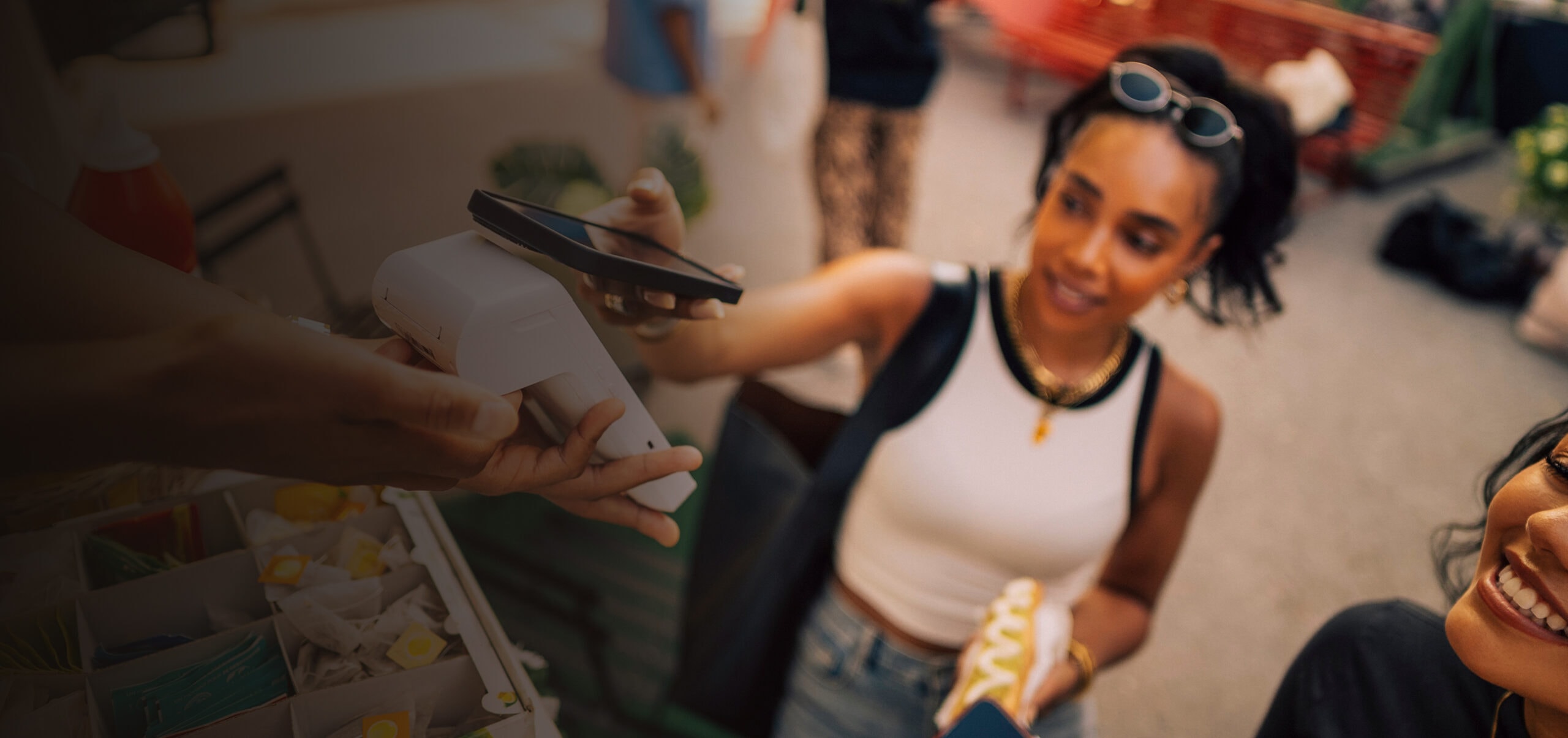 A young woman purchasing a hotdog by paying with her phone